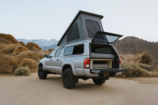 A truck with a camper cap parked by a stunningly blue lake in the Canadian Rockies at sunrise.